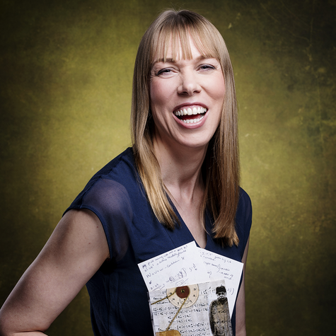 Professor Catherine Heymans smiling at the camera, holding a copy of Einstein's Theory of Relativity